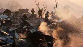 Firefighters remove the remains of a burned house on a hill, where more than 100 homes were burned due to forest fire but there have been no reports of death, local authorities said in Valparaiso, Chile