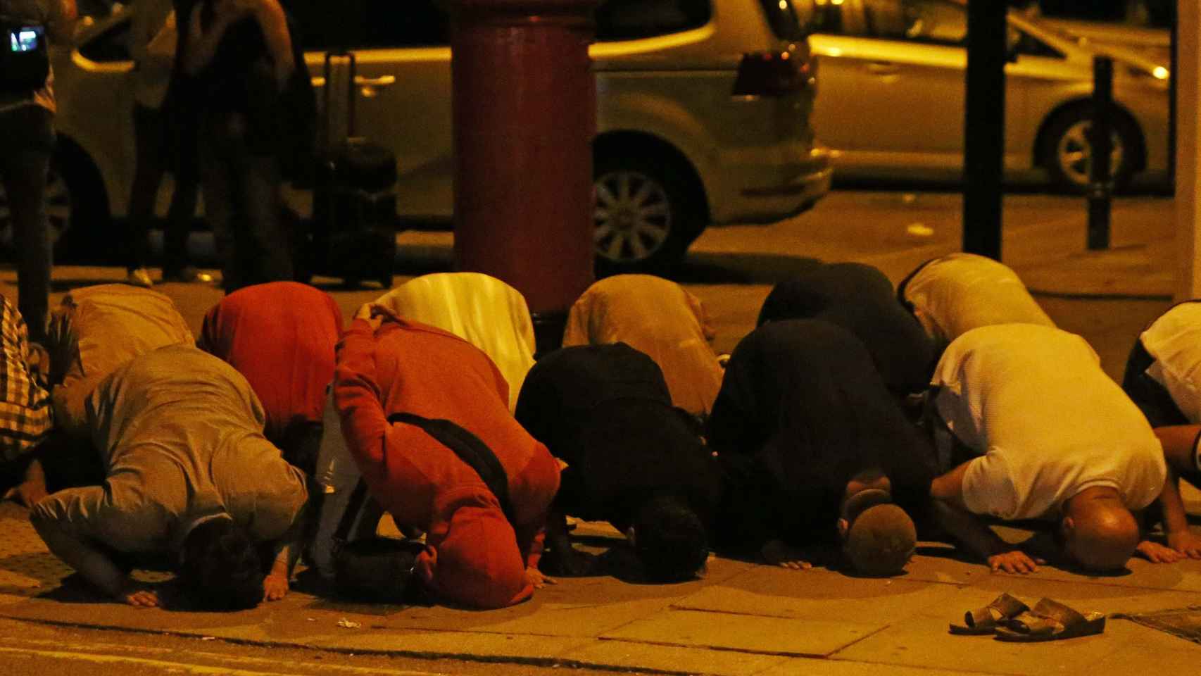 Un grupo de musulmanes reza en el suelo de la calle. / Reuters
